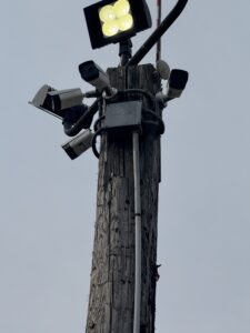 Utility pole with four security cameras and a floodlight installed at the top