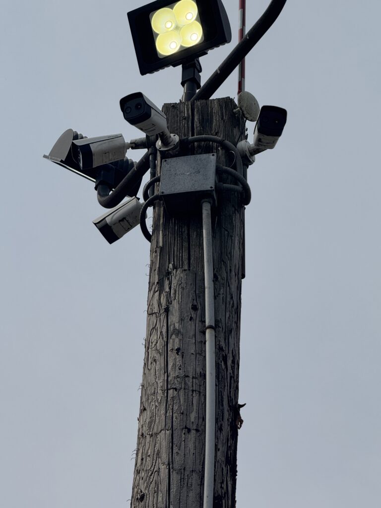 Utility pole with four security cameras and a floodlight installed at the top
